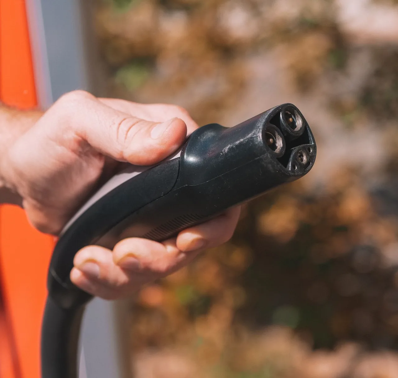 A hand holding an electric vehicle charging connector